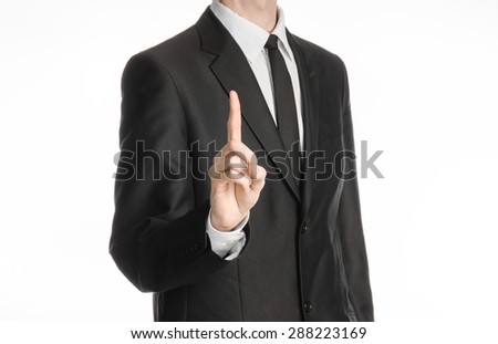 Businessman and gesture topic: a man in a black suit with a tie shows an index finger upward on white isolated background in studio