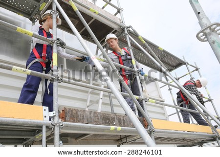 Construction workers installing scaffolding on site Royalty-Free Stock Photo #288246101