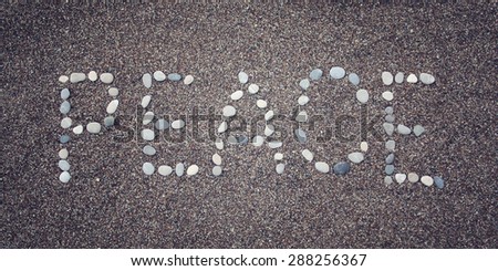 'Peace' word written with pebbles on the sand. Aged photo. 'Peace' word made by small stones on the beach. Word on the sand - toned photo. Antalya Province, Turkey. Wide photo for site slider.