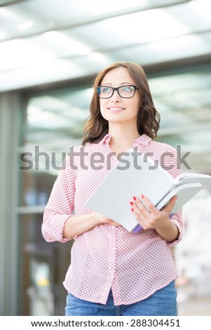 Thoughtful woman looking away while holding book outdoors