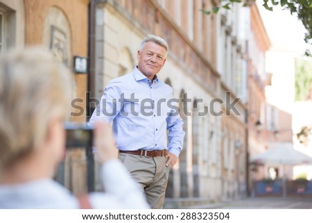 Middle-aged woman taking picture of man in city
