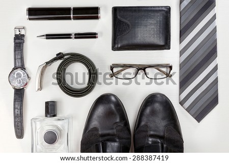 Men accessories. Black elegant accessories pieces isolated on white wooden table. Top view. Royalty-Free Stock Photo #288387419