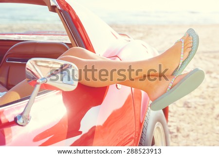 Relaxed woman legs and flip flops in a car window on the beach Royalty-Free Stock Photo #288523913