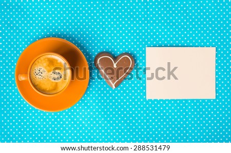 ceramic cup with coffee  espresso, tablet for text, chocolate marzipan candy heart on a bright blue background, love concept, have a nice day, good morning, good day, happy Valentine's Day, top view
