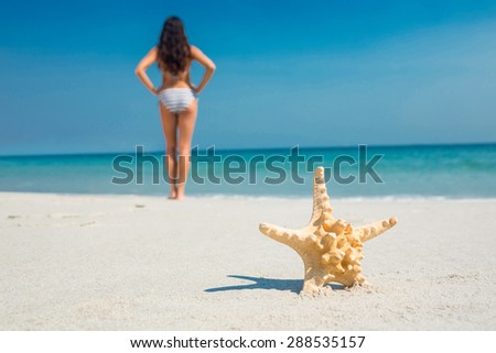 Pretty brunette and starfish on the beach on a sunny day