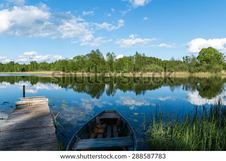 White clouds on the blue sky over blue lake with reflections with boats and boardwalk