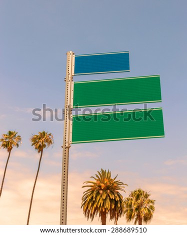 Empty road signs with palms and blue sky with copyspace at sunset