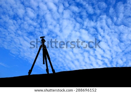 Silhouette of tripod under the blue sky.