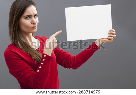 judge mental young lady pointing at a blank message on board and wearing a red sweater