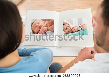 Close-up Of Couple Looking At Baby's Photo Album