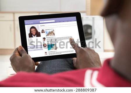 Close-up Of African Young Man Chatting On Social Networking Site Using Digital Tablet