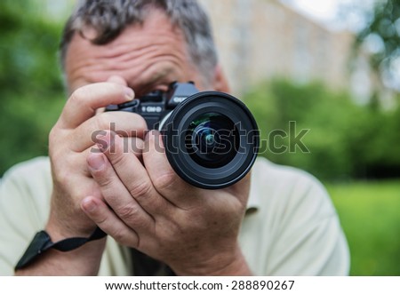 Photographer using a dslr camera with a green background