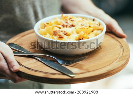 Plate of macaroni with cheese and bacon in hands. Toned picture