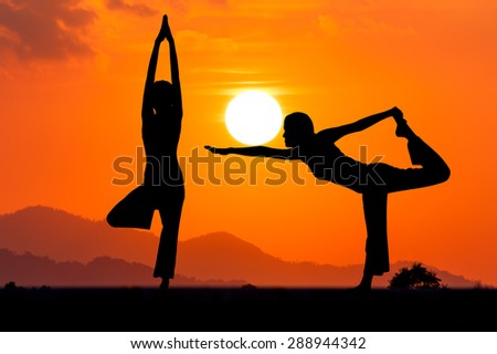 Silhouette young woman practicing yoga  at orange sunset on the mountain background