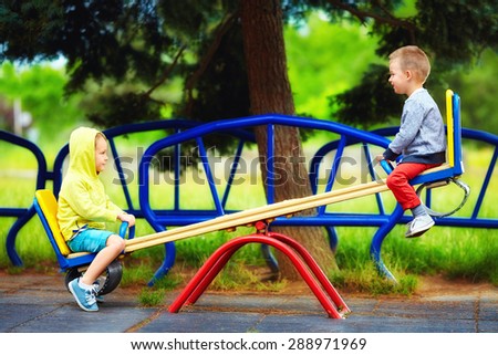 cute kids having fun on seesaw at playground Royalty-Free Stock Photo #288971969