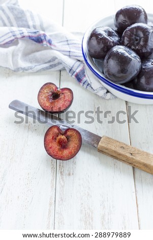 Plums Plums whole and sliced on a white rustic background