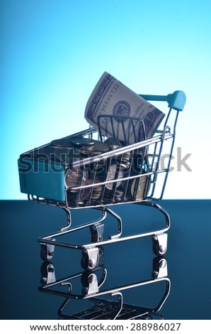 Shopping cart loaded with coins and money : saving and consumer concept