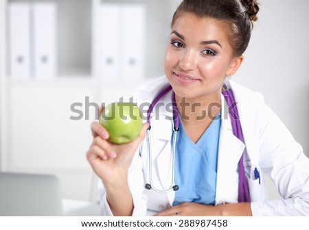 Female doctor hand holding a green apple, standing .