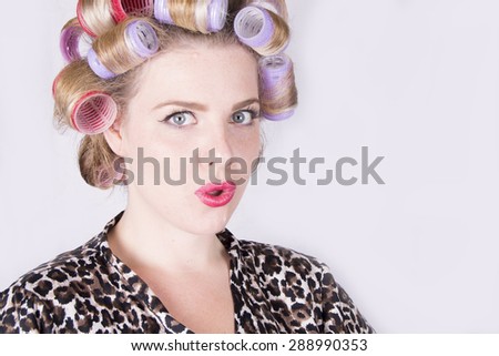 Beautiful blonde woman with curlers wearing a leopard print bathrobe (studio, white background)