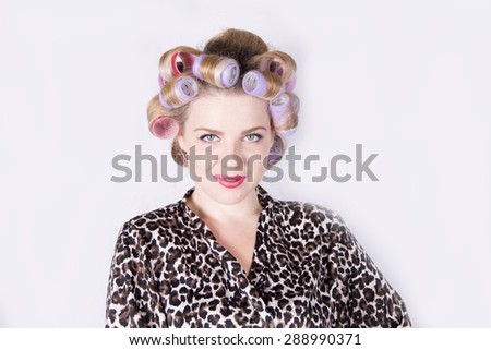 Beautiful blonde woman with curlers wearing a leopard print bathrobe (studio, white background)