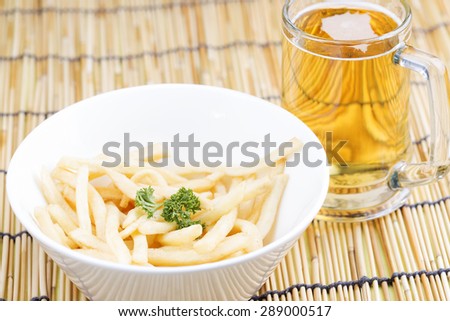 Fresh french fries in a bowl with glass of beers