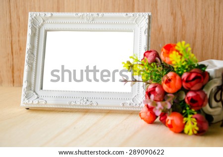 Flowers vase and vintage white picture frame on wooden desktop, clipping path