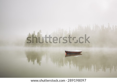 Boat on the lake at morning fog. Royalty-Free Stock Photo #289198097