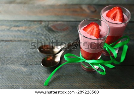 Fresh strawberry yogurt dessert in glass, on color wooden background