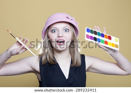 Surprised woman with paint and brush on beige background