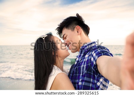 Couple taking self portrait photos with smart phone on the beach