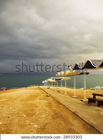 Beach umbrellas on deserted coast of the Dead Sea in thunder-storm