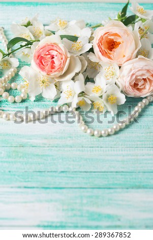 Pastel sweet roses and jasmine flowers on turquoise wooden background. Place for text. Selective focus is  on middle rose. Toned image.