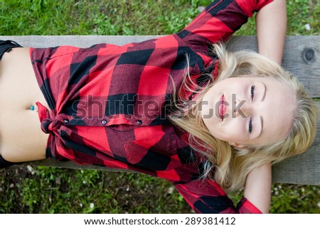 beautiful blonde young woman sleeping relaxed on a bench in a park or on the woods
