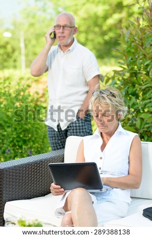 a man on phone and his wife on  computer outside
