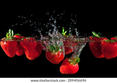 Strawberries splashing into water on a black background
