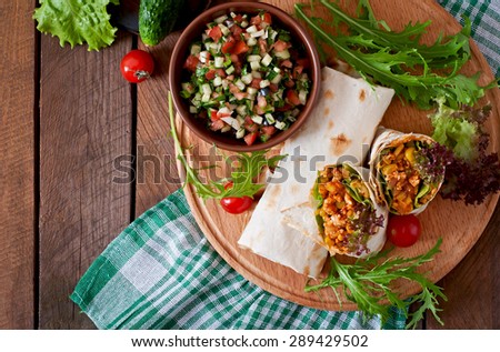 Burritos wraps with minced beef and vegetables on a wooden background. Top view