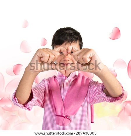 Boy making a heart with his hands over hearts background