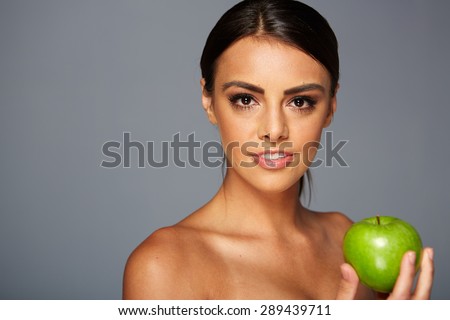 Smiling woman with apple isolated on gray