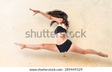 Young ballet dancer jumping over textured background
