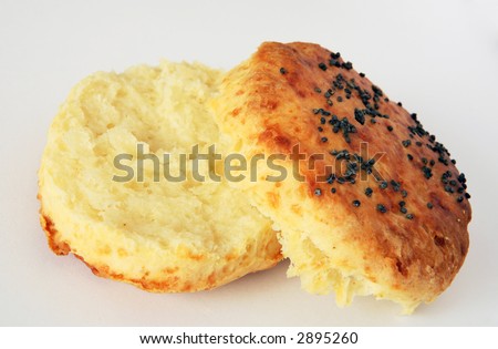 A cheese scone, topped with poppy seeds, in two halves ready for buttering.