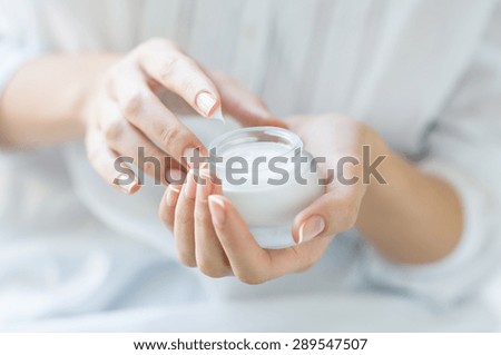 Closeup shot of hands applying moisturizer. Beauty woman holding a glass jar of skin cream. Shallow depth of field with focus on moisturizer. Royalty-Free Stock Photo #289547507