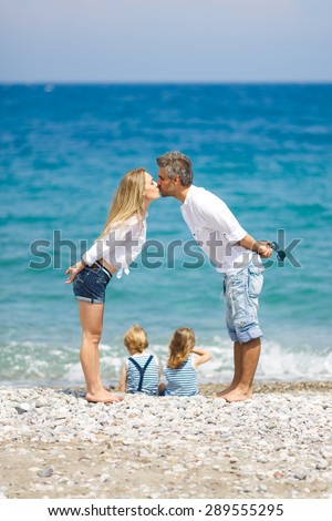 Happy mother and father with two sitting kids on the beach