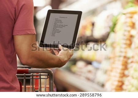Close Up Of Man Reading Shopping List From Digital Tablet In Supermarket
