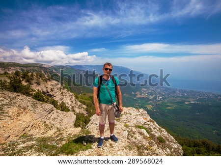 Traveler with backpack enjoying a view of valley from the mountain tops