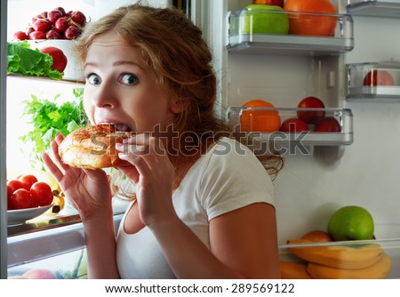 woman eats sweets at night to sneak in a refrigerator Royalty-Free Stock Photo #289569122