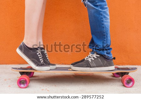 Closeup kissing couple at skateboard and red wall background. Image ready for International, World Kissing Day 6 July or Valentine's Day