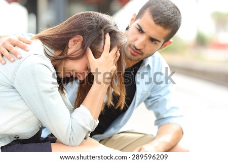 Side view of a muslim man comforting a sad caucasian girl mourning in a train station Royalty-Free Stock Photo #289596209