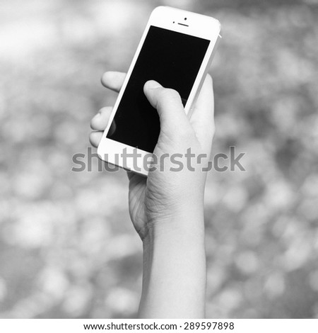 Woman hand holding smartphone against on background black and white color