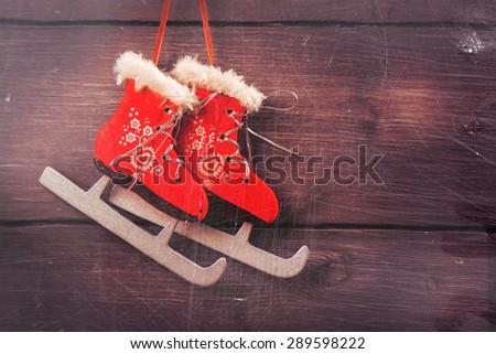 Xmas card: red skates over vintage wooden background. Toned image with scratches