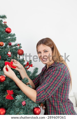 Beautiful woman putting a bow in the christmas tree